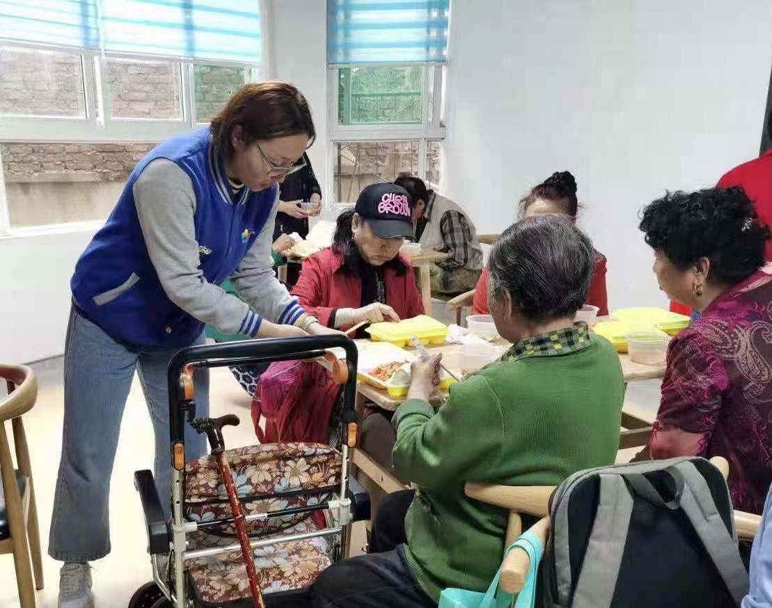 图3 社工站社工引导行动不便的老人落座就餐.jpg